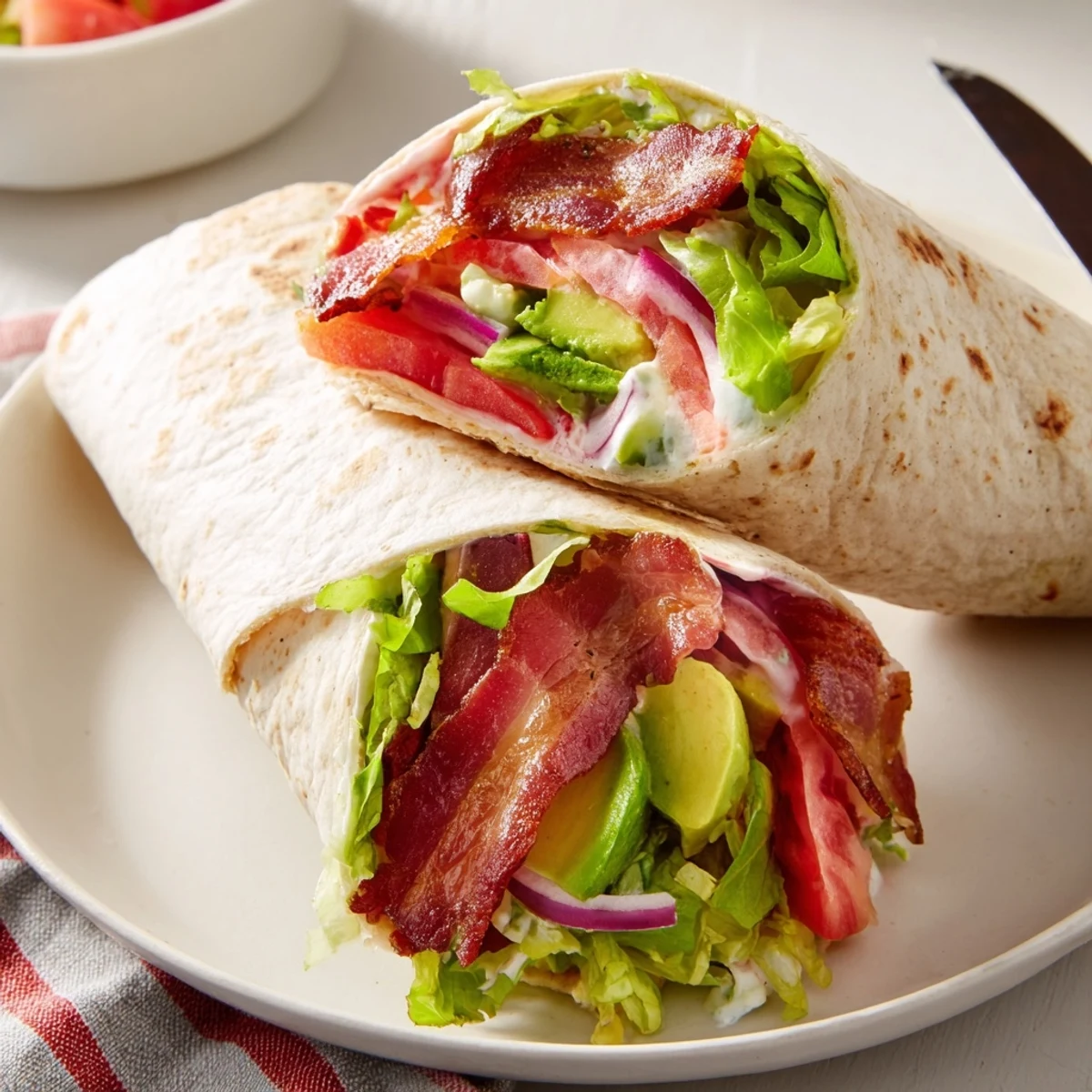 Sliced on a board, Meal Prep BLT Wraps show creamy dressing and bacon