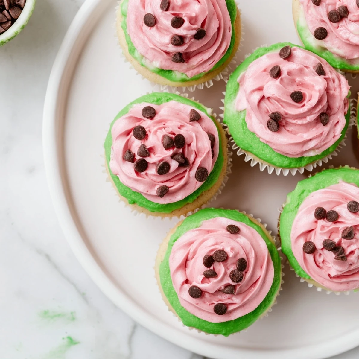 Freshly baked watermelon cupcakes with creamy pink frosting decorated like sliced summer watermelon