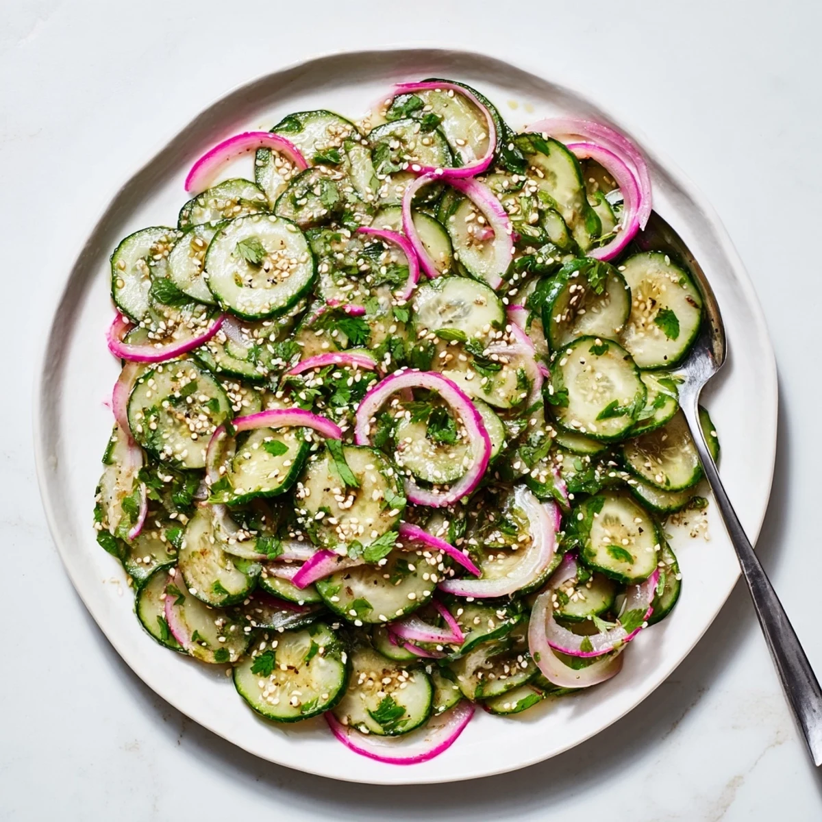 Colorful bowl of honey lime cucumber salad tossed with red onion and fresh herbs in a sweet citrus glaze