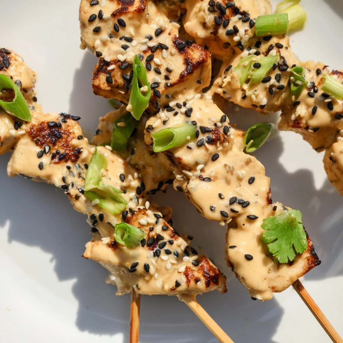 Golden Bang Bang Chicken skewers coated in creamy spicy sauce and sprinkled with sesame seeds
