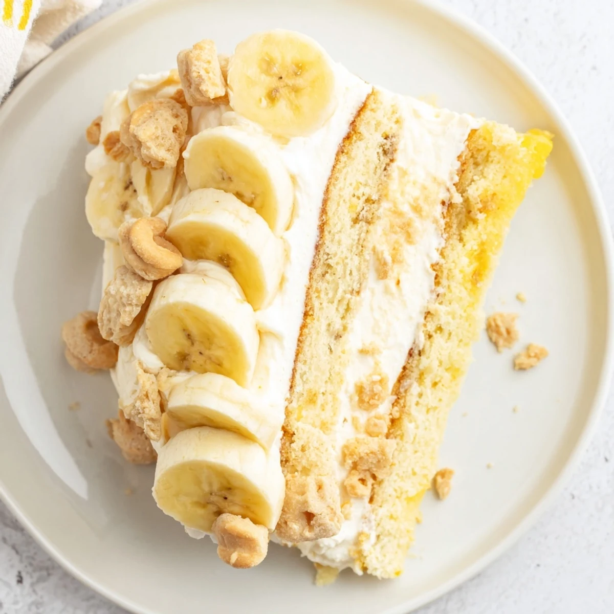 Golden banana pudding cake slice revealing pudding-filled layers between tender banana-spiced cake and crunchy cookies