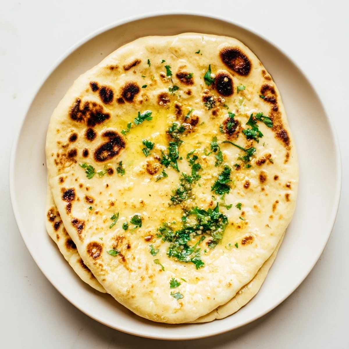 Golden brown sourdough discard soft naan brushed with melted butter and fresh herbs