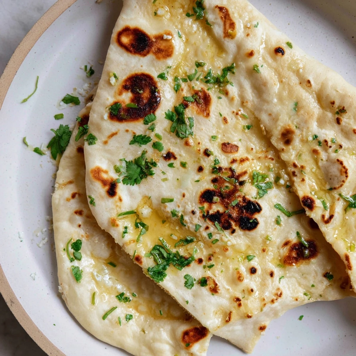 Soft sourdough discard naan bread stacked on a wooden board ready for dipping