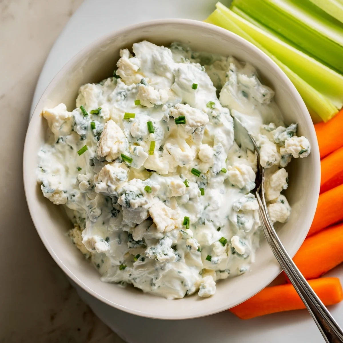 Thick blue cheese dip topped with fresh chives in a rustic serving bowl
