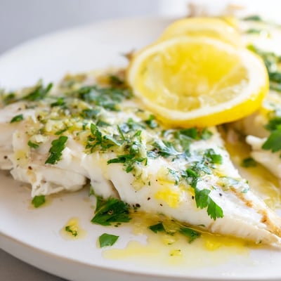 Delicious Baked Halibut with Lemon Butter Sauce served alongside roasted potatoes and asparagus for an elegant dinner.