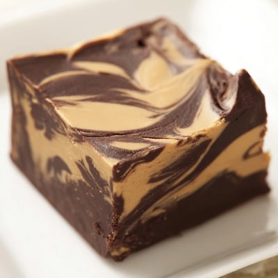 Freshly cut Chocolate Peanut Butter Fudge Squares show creamy layers and a soft crumb on a clean wooden cutting board.