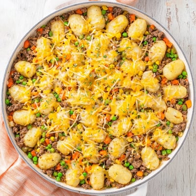 Comforting spoonfuls of Quick Gnocchi Shepherds Pie reveal pillowy gnocchi, melted cheddar, and peas in a rich sauce.