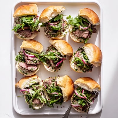Freshly seared steak rests on soft slider buns spread with zesty herb-packed cowboy butter in this savory meal.
