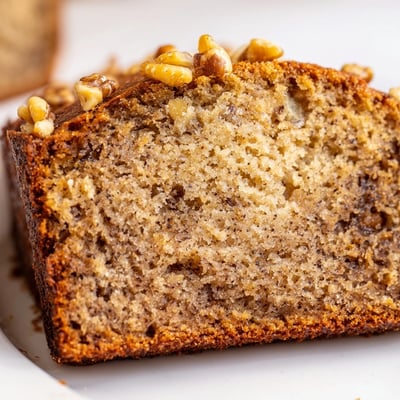 Moist banana nut bread topped with crunchy pecans on a wire cooling rack