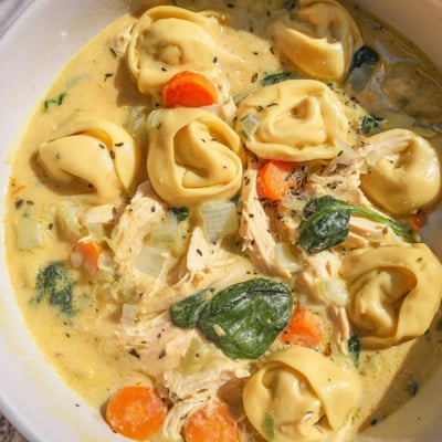 Steaming bowl of crockpot chicken tortellini topped with melted Parmesan and tender vegetables